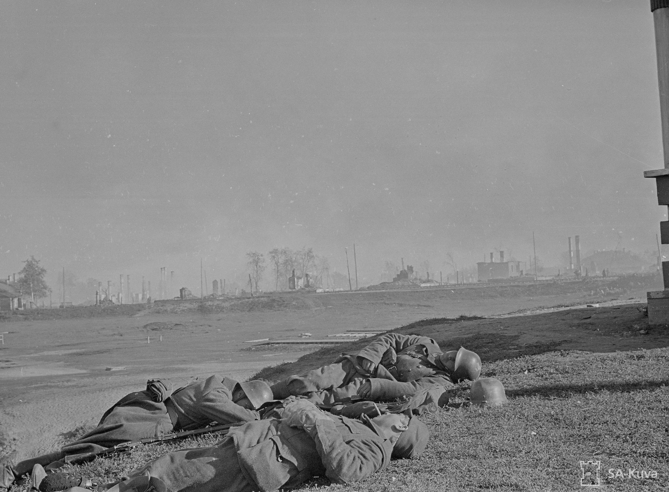 Suomalaisia sotilaita lepäämässä tuhoutuneessa Petroskoissa 1941. Kuva: Erik Blomberg, SA-kuva.